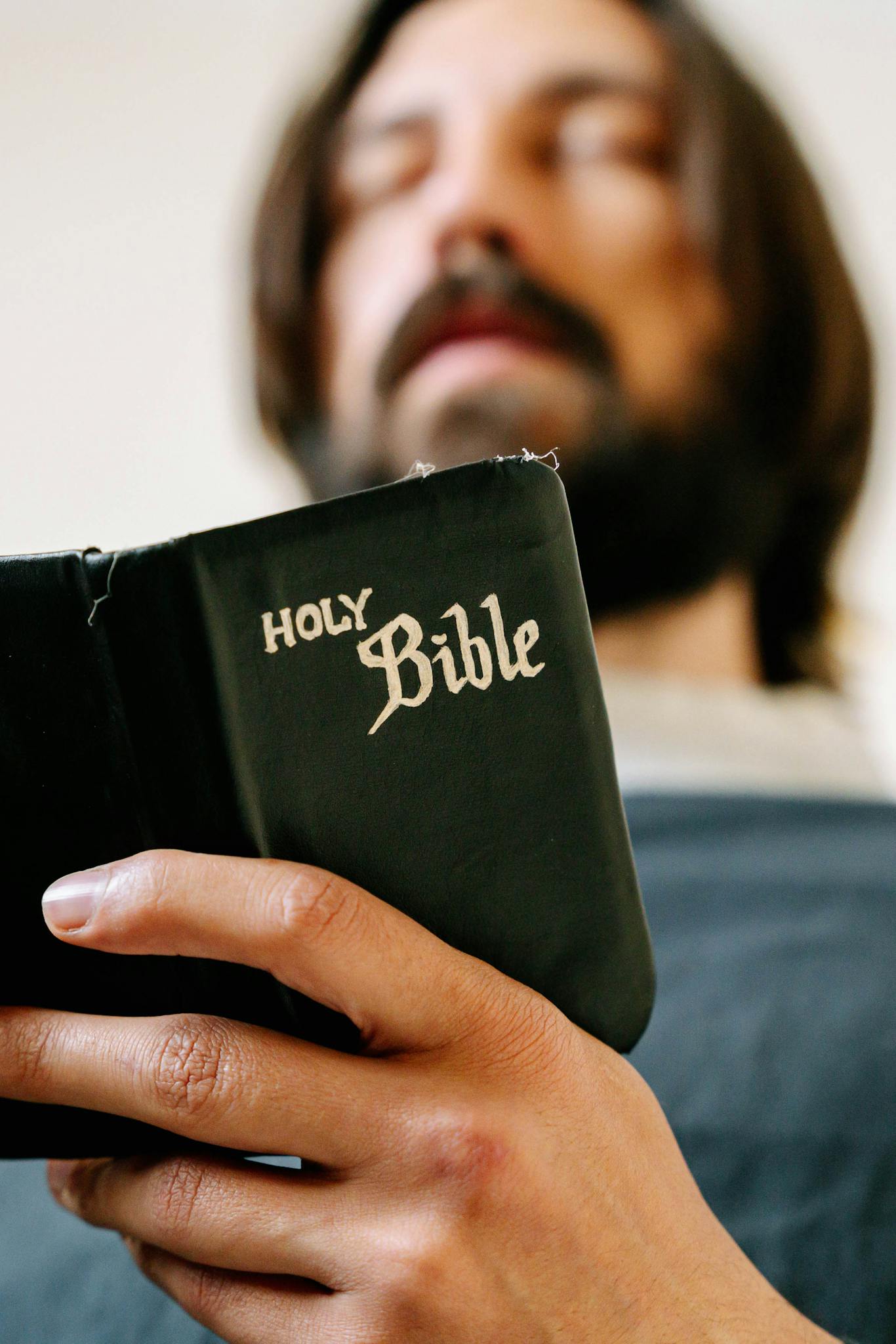 Bearded Man Holding a Holy Bible Praying with Eyes Closed